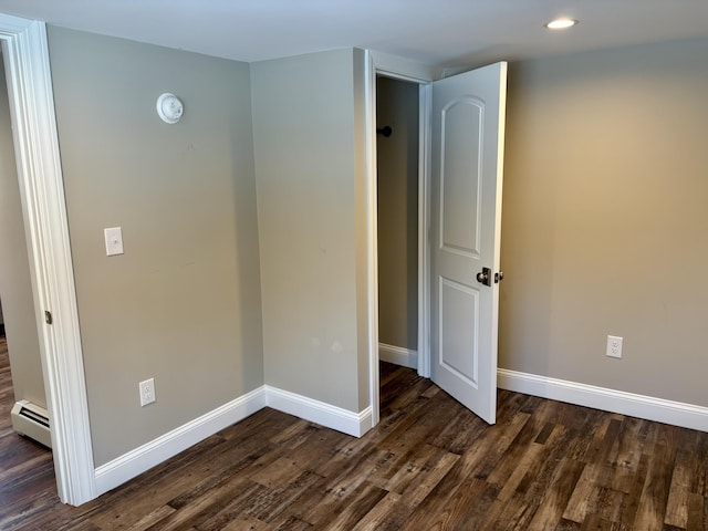 empty room featuring baseboards, dark wood finished floors, and baseboard heating