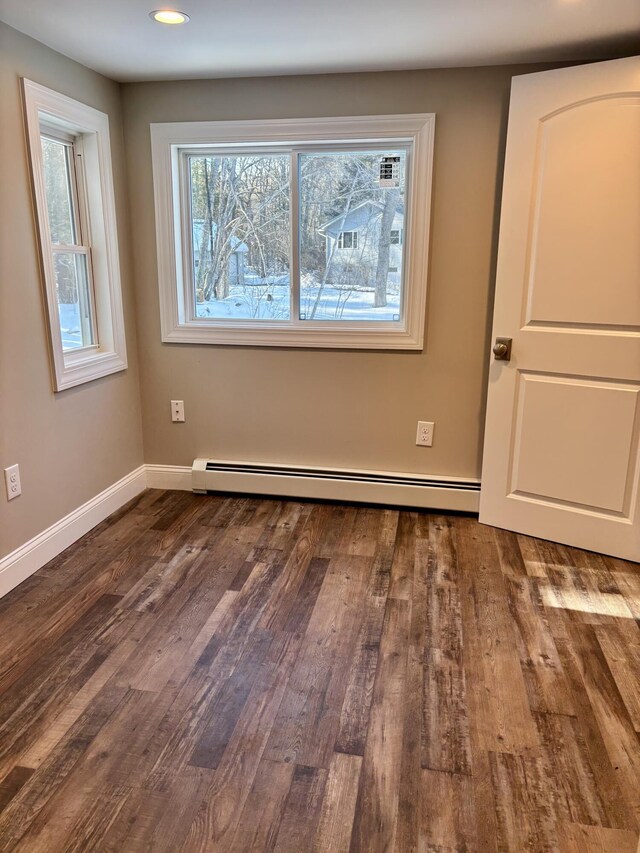 empty room with a baseboard heating unit, recessed lighting, dark wood finished floors, and baseboards