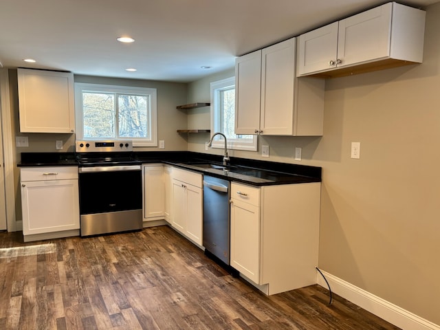 kitchen with a sink, stainless steel appliances, dark countertops, and open shelves