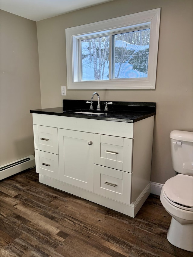 bathroom with toilet, baseboard heating, wood finished floors, and vanity