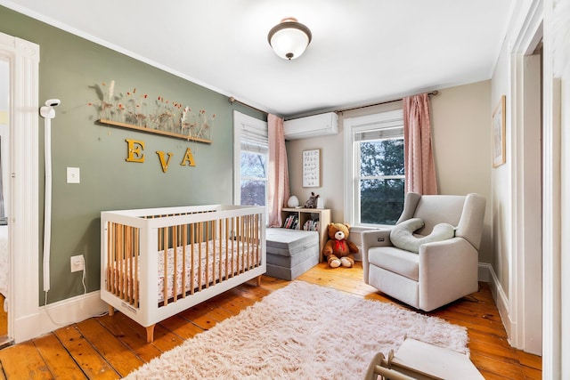 363 Broadway, Bangor, ME 04401 - bedroom with an AC wall unit, wood-type flooring, a nursery area, and baseboards