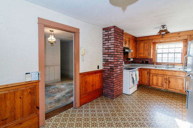 kitchen featuring stainless steel fridge, backsplash, white electric range oven, wooden walls, and sink