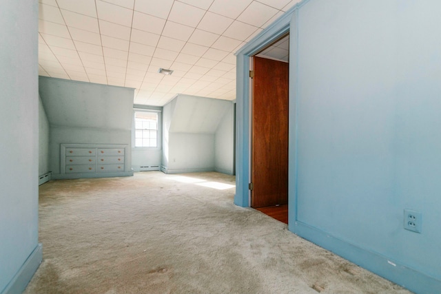 additional living space featuring light colored carpet, vaulted ceiling, and a baseboard heating unit