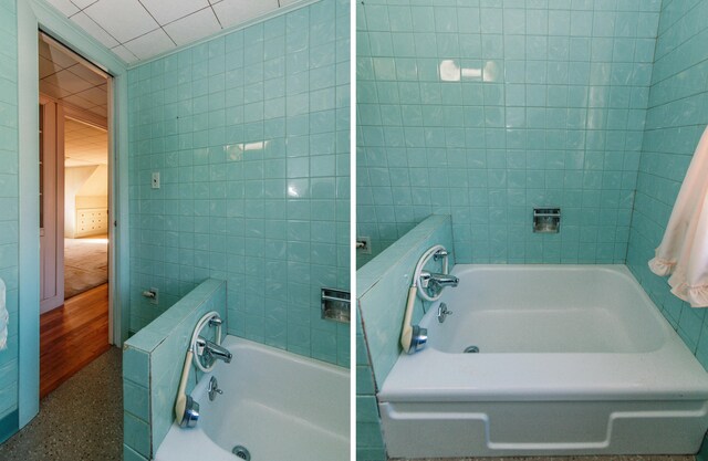 bathroom featuring a washtub and tile walls