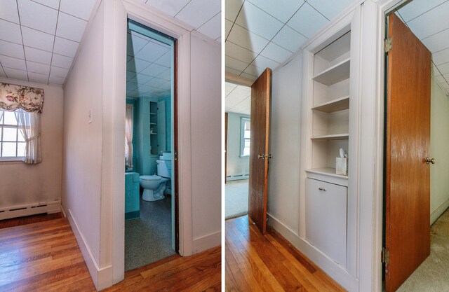 hall with built in shelves, light hardwood / wood-style floors, and a baseboard radiator