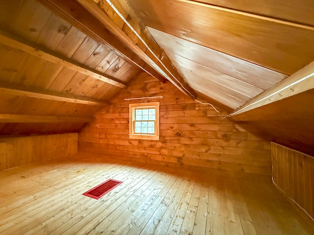 additional living space featuring lofted ceiling with beams, wood walls, wood-type flooring, and wooden ceiling