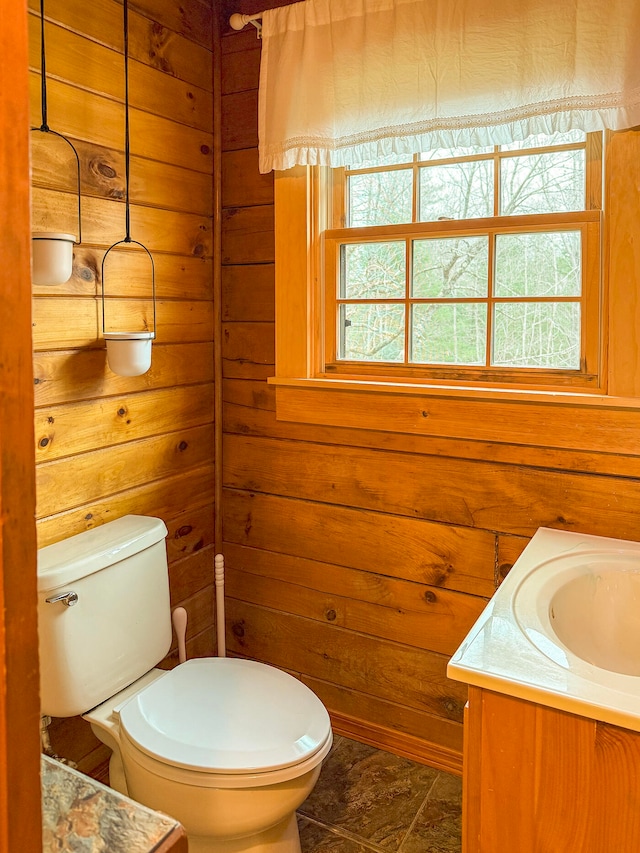 bathroom with vanity, toilet, and wood walls