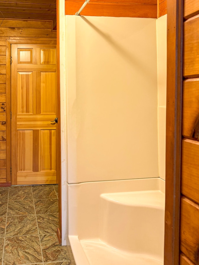 bathroom featuring a shower and wood walls