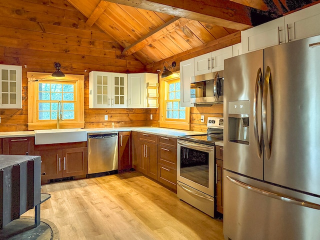 kitchen featuring appliances with stainless steel finishes, sink, lofted ceiling with beams, white cabinets, and light hardwood / wood-style floors