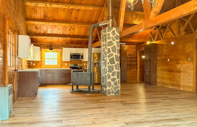 kitchen with wood walls, wooden ceiling, stainless steel appliances, and light hardwood / wood-style flooring