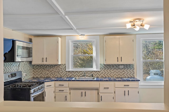 kitchen featuring cream cabinets, stainless steel appliances, tasteful backsplash, and sink