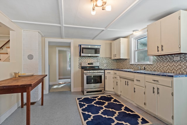 kitchen with cream cabinetry, backsplash, stainless steel appliances, and sink