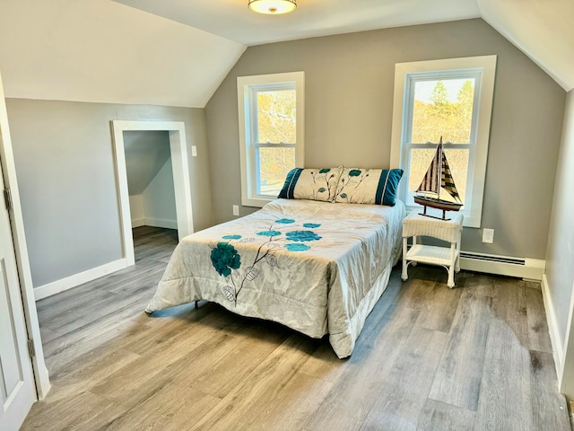 bedroom featuring hardwood / wood-style floors, baseboard heating, and multiple windows