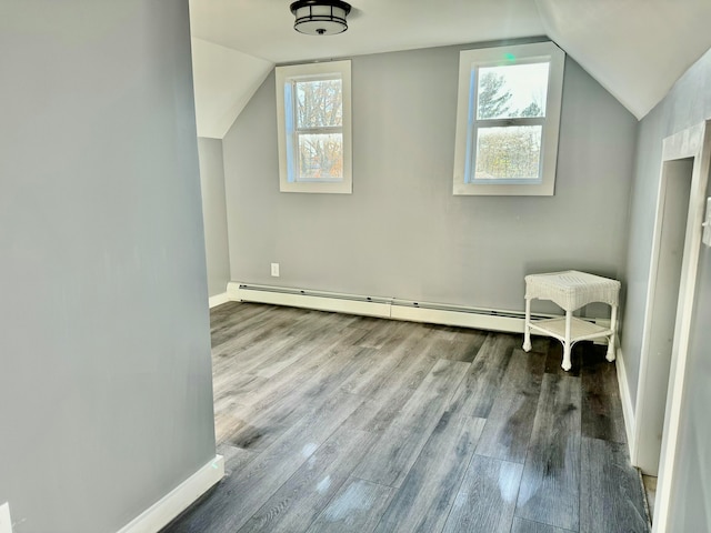 additional living space with light wood-type flooring, baseboard heating, and vaulted ceiling