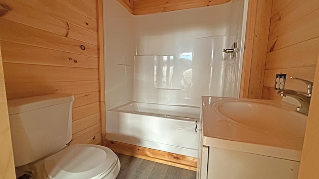 full bathroom featuring wood walls, hardwood / wood-style floors, toilet, vanity, and bathtub / shower combination