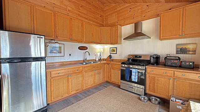 kitchen featuring sink, wall chimney range hood, stainless steel appliances, and dark wood-type flooring