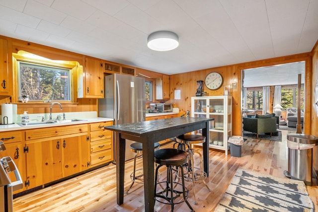 kitchen with a wealth of natural light, stainless steel fridge, sink, and wood walls