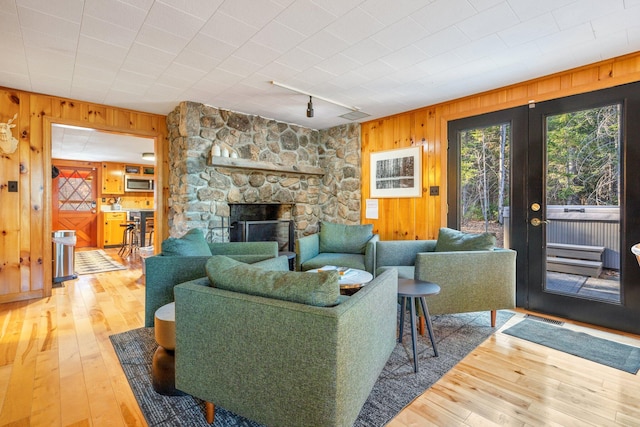 living room with hardwood / wood-style flooring, wood walls, and a fireplace