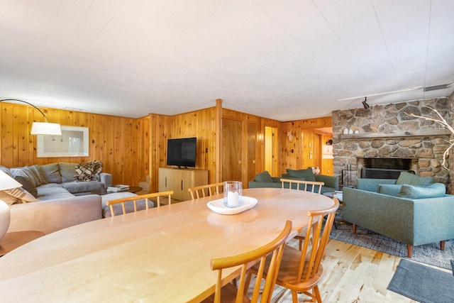 dining room featuring wooden walls, a fireplace, and light wood-type flooring