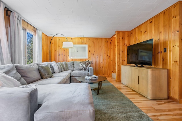 living room with light wood-type flooring and wood walls