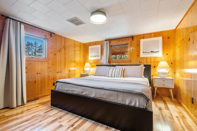 bedroom with wood walls and light wood-type flooring