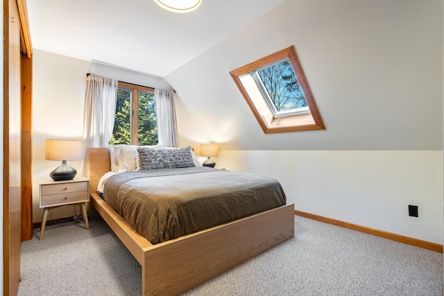 bedroom with vaulted ceiling with skylight and carpet floors