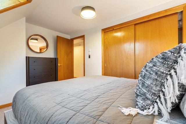 carpeted bedroom with a closet and vaulted ceiling