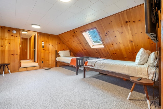 bedroom featuring a skylight, wooden walls, and carpet