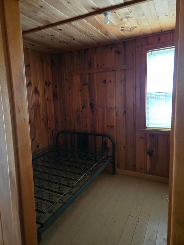 unfurnished bedroom with wooden ceiling, light hardwood / wood-style flooring, and wooden walls