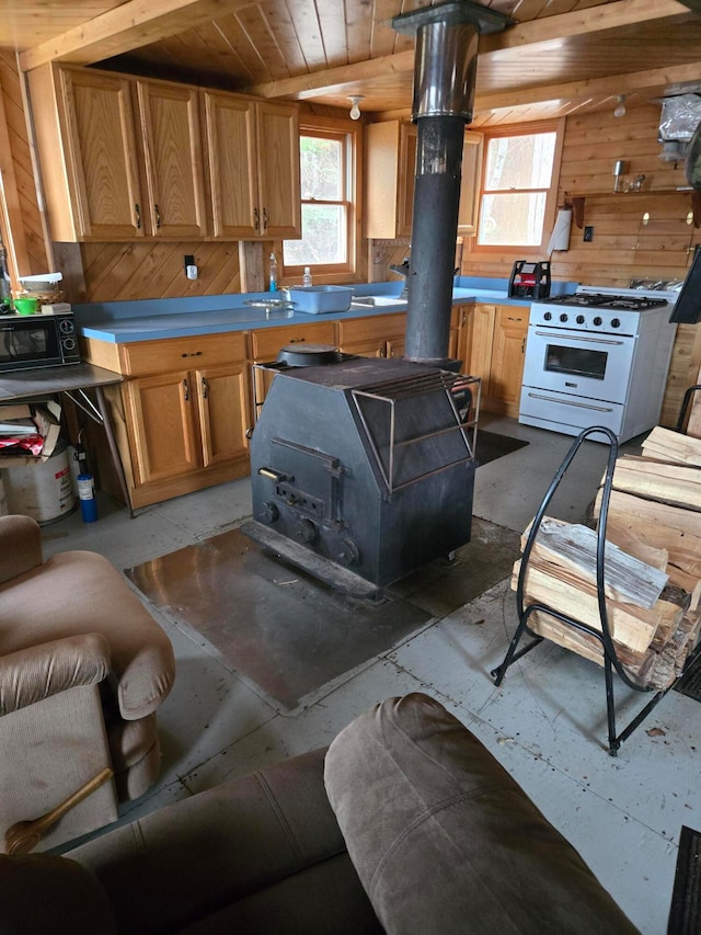 kitchen featuring wood ceiling, gas range gas stove, and wood walls