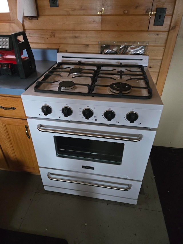 kitchen with white gas range oven and wooden walls