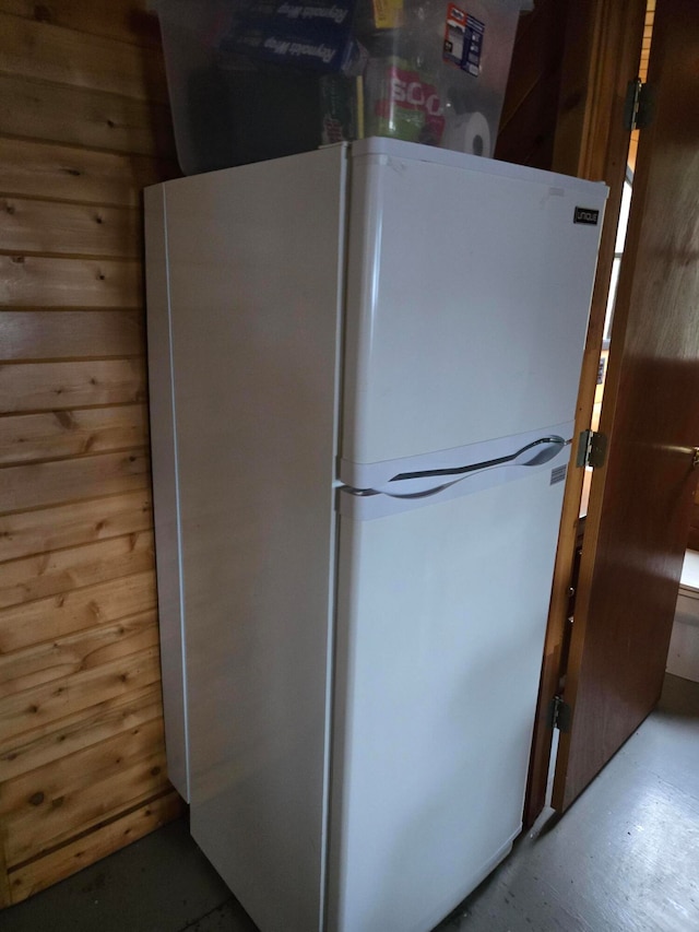 kitchen featuring white fridge and wooden walls