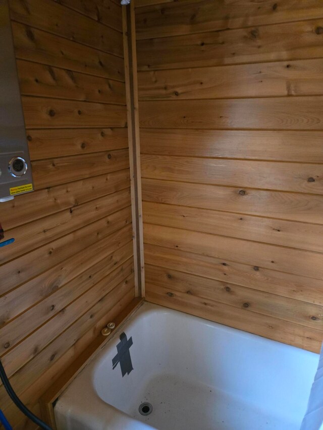 bathroom featuring a bathing tub and wooden walls