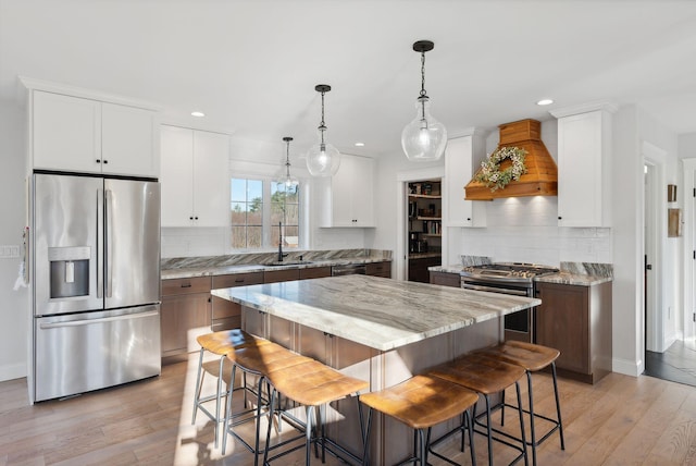 kitchen featuring white cabinets, a kitchen island, stainless steel appliances, and light wood-type flooring