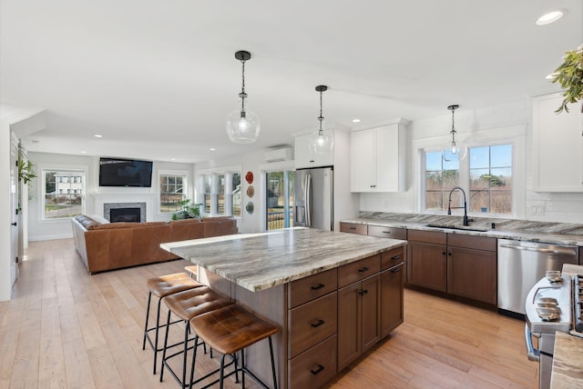 kitchen with stainless steel appliances, sink, light hardwood / wood-style flooring, white cabinets, and a kitchen island