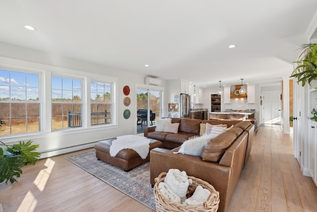 living room with baseboard heating, light hardwood / wood-style flooring, and a wall unit AC