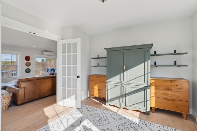 miscellaneous room with light wood-type flooring and a wall unit AC