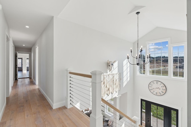 corridor featuring hardwood / wood-style flooring, lofted ceiling, and an inviting chandelier