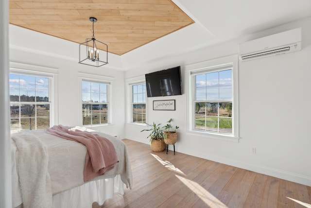 bedroom with hardwood / wood-style floors, an inviting chandelier, a wall mounted air conditioner, and multiple windows