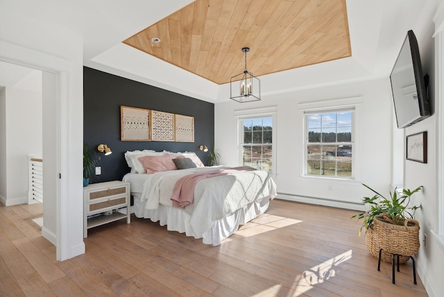 bedroom with wooden ceiling, light hardwood / wood-style flooring, baseboard heating, a tray ceiling, and a chandelier