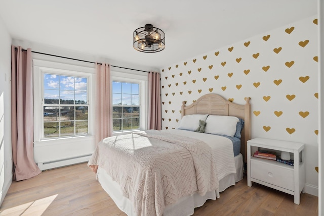 bedroom with light wood-type flooring and baseboard heating