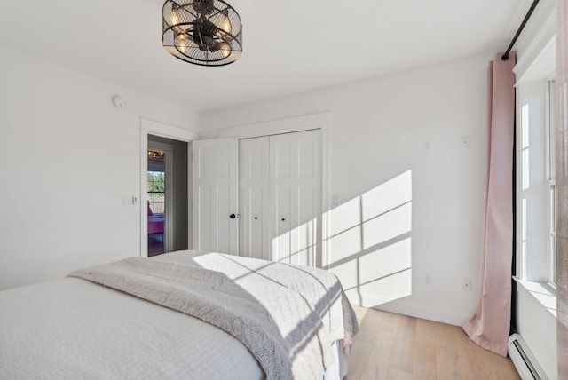 bedroom featuring a baseboard radiator, light hardwood / wood-style flooring, and a closet