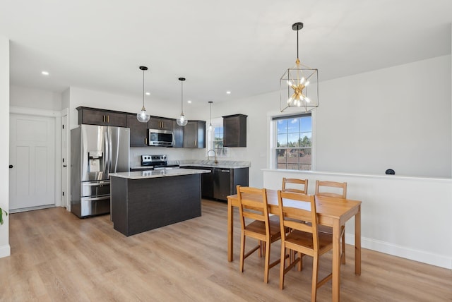 kitchen with pendant lighting, a kitchen island, light wood-type flooring, and stainless steel appliances