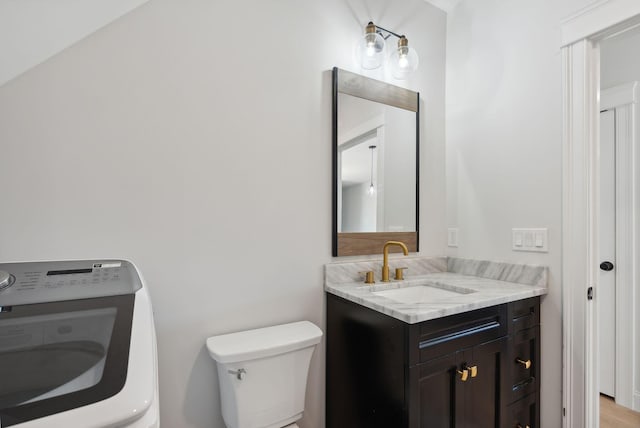 bathroom featuring hardwood / wood-style flooring, toilet, vanity, and washer / dryer