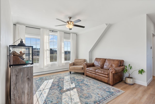 living room featuring light wood-type flooring, ceiling fan, and a baseboard heating unit