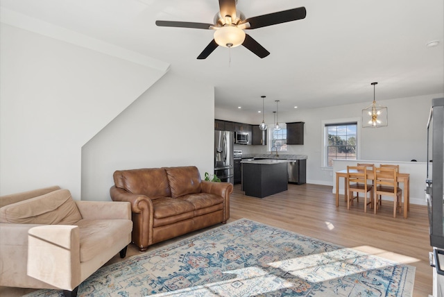 living room with light hardwood / wood-style flooring, ceiling fan, and sink