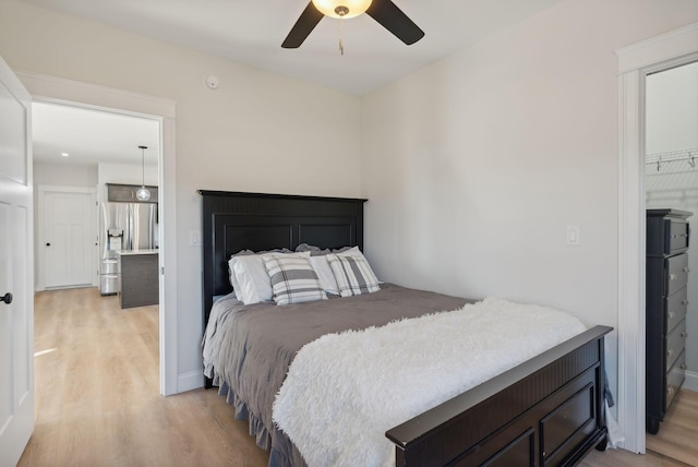 bedroom with ensuite bath, ceiling fan, stainless steel refrigerator with ice dispenser, and light wood-type flooring