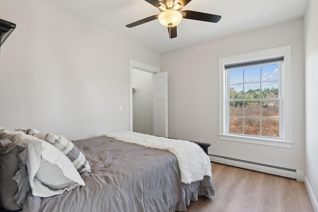 bedroom with light hardwood / wood-style floors, ceiling fan, and a baseboard heating unit