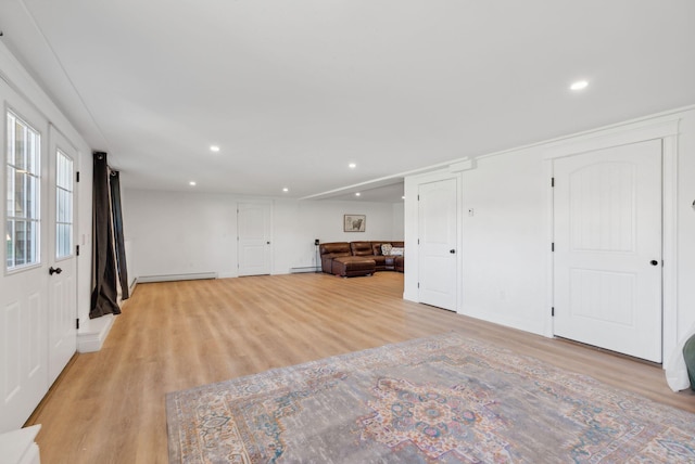 interior space with a baseboard heating unit and light hardwood / wood-style flooring