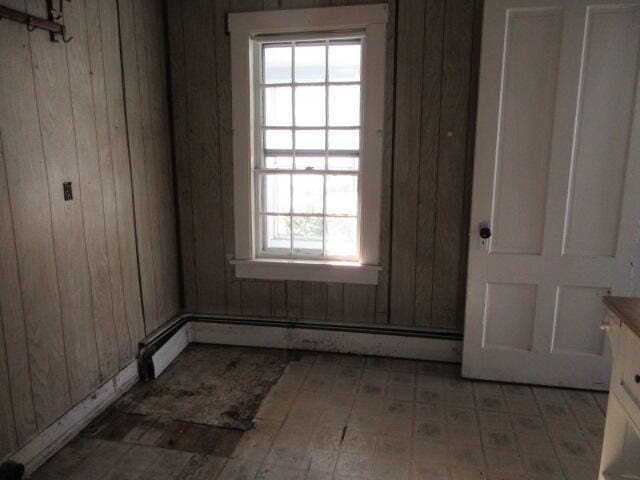 spare room with baseboard heating and wooden walls